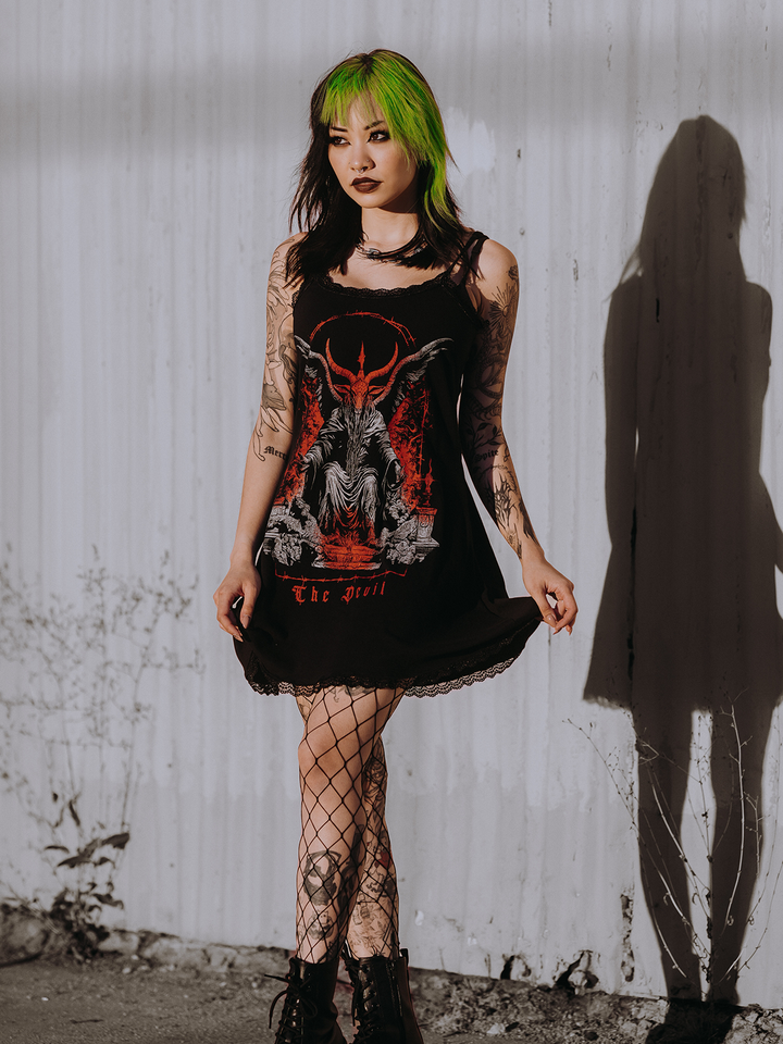 A model standing outside wearing a black lace trimmed mini dress with custom Blackcraft artwork on the front.
