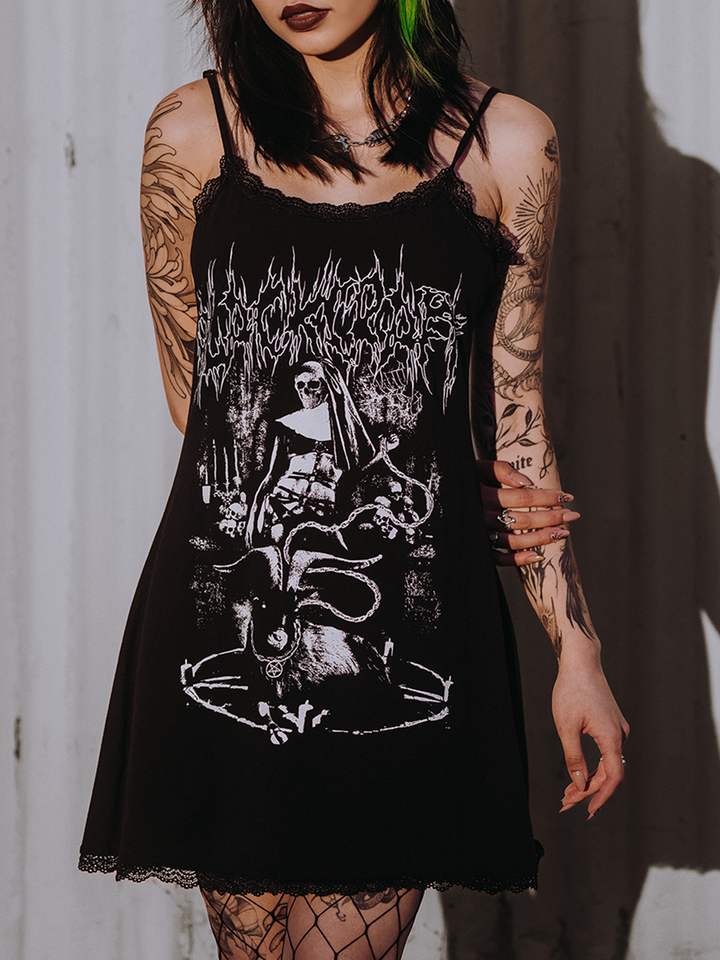 A model standing outside wearing a black lace trimmed mini dress with custom Blackcraft artwork on the front.