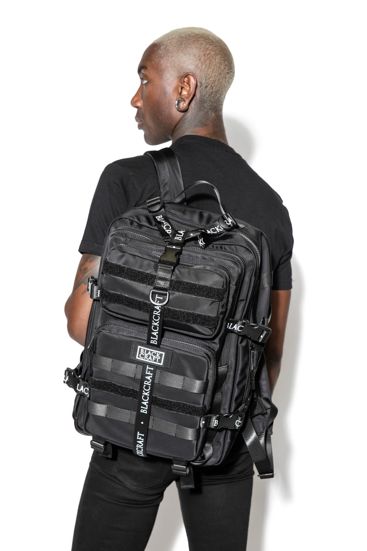 Large black nylon backpack with Blackcraft rubber logo, functional buckles, and logo strap details.