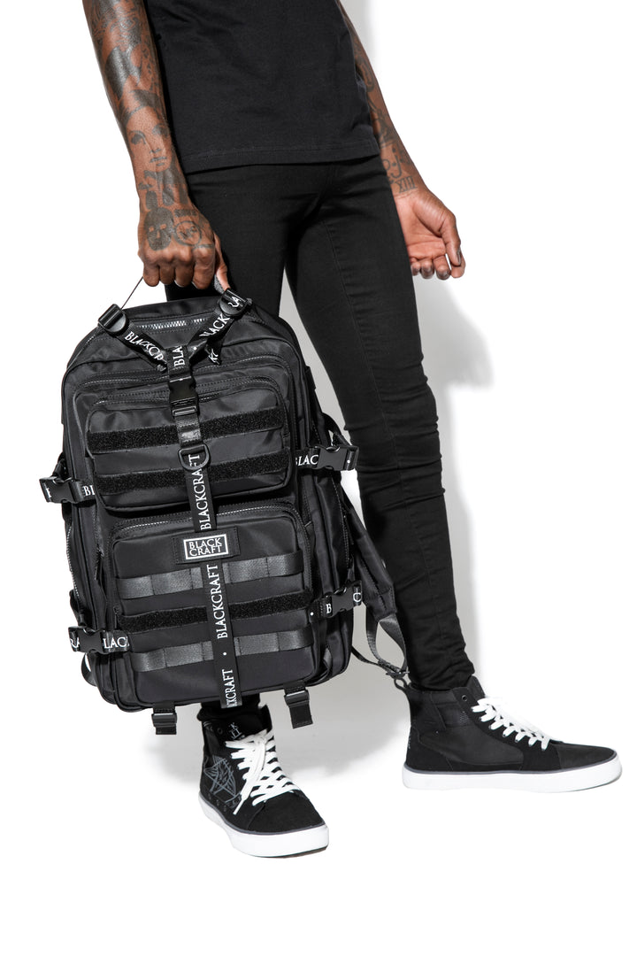 Large black nylon backpack with Blackcraft rubber logo, functional buckles, and logo strap details.