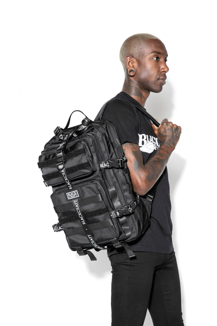 Large black nylon backpack with Blackcraft rubber logo, functional buckles, and logo strap details.
