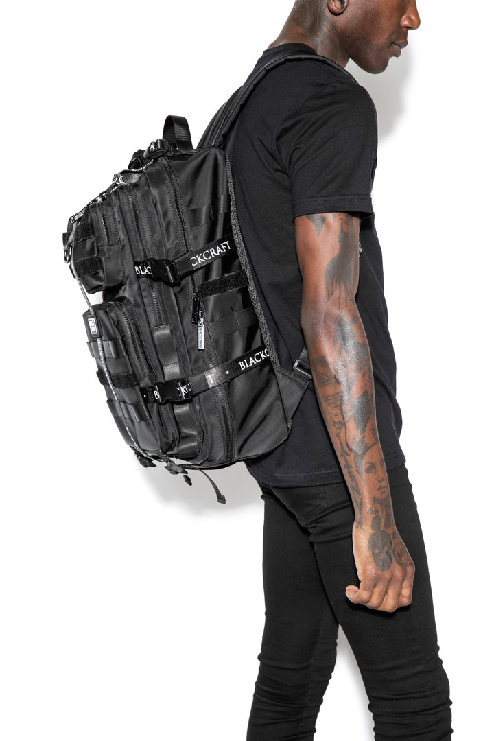 Large black nylon backpack with Blackcraft rubber logo, functional buckles, and logo strap details.