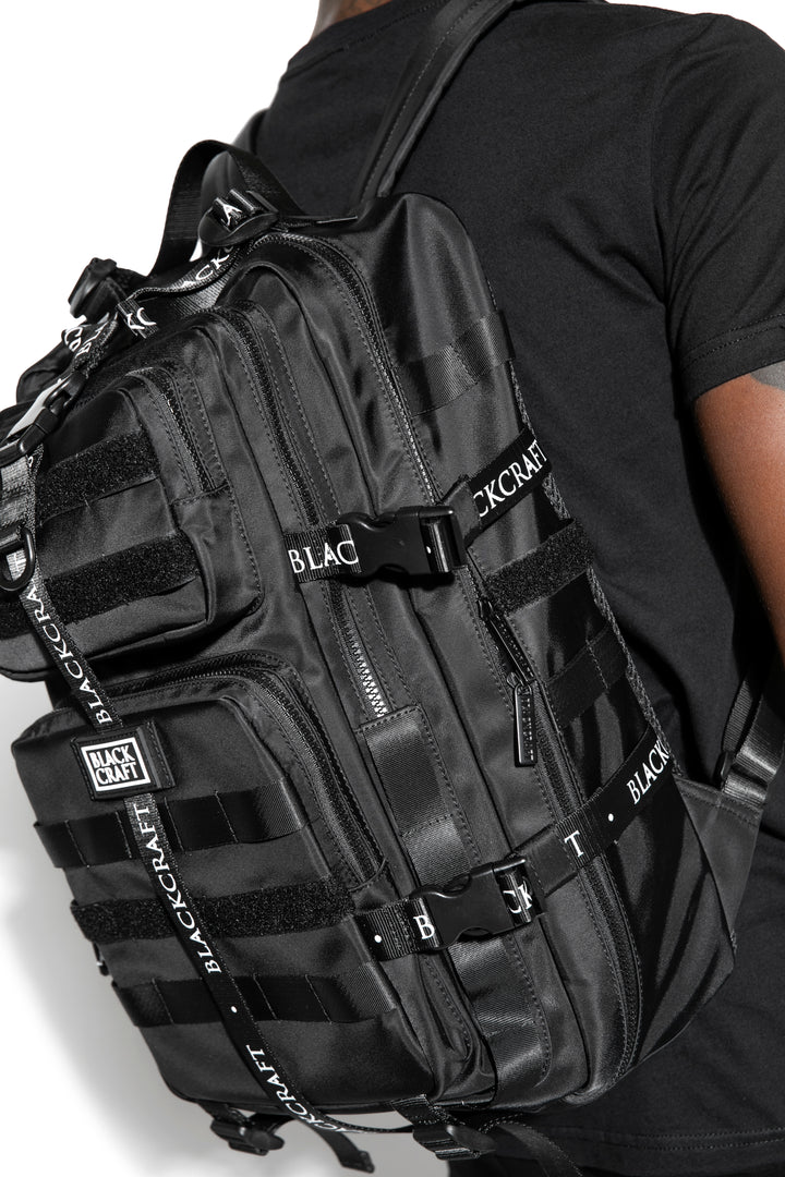 Large black nylon backpack with Blackcraft rubber logo, functional buckles, and logo strap details.