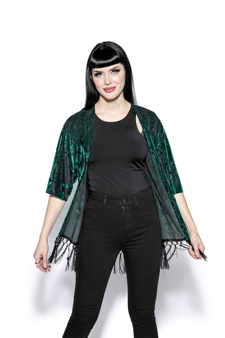 A gothic velvet kimono cover up with fringed trim, an open front, and kimono half length sleeves.