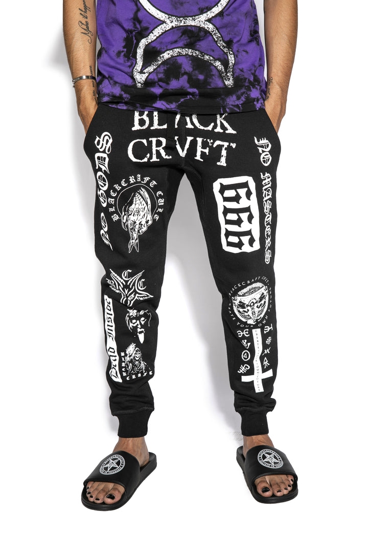 A model wearing a pair of classic fit black joggers with custom Blackcraft artwork along the front of each leg.