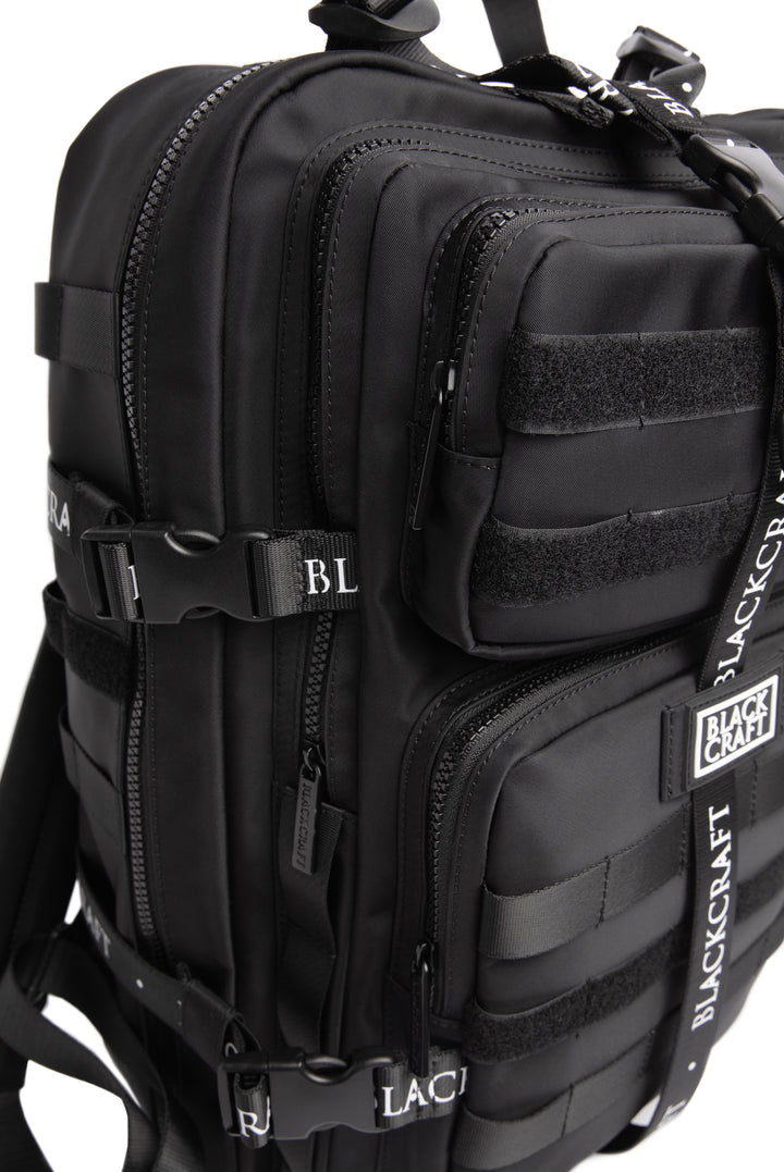 Large black nylon backpack with Blackcraft rubber logo, functional buckles, and logo strap details.