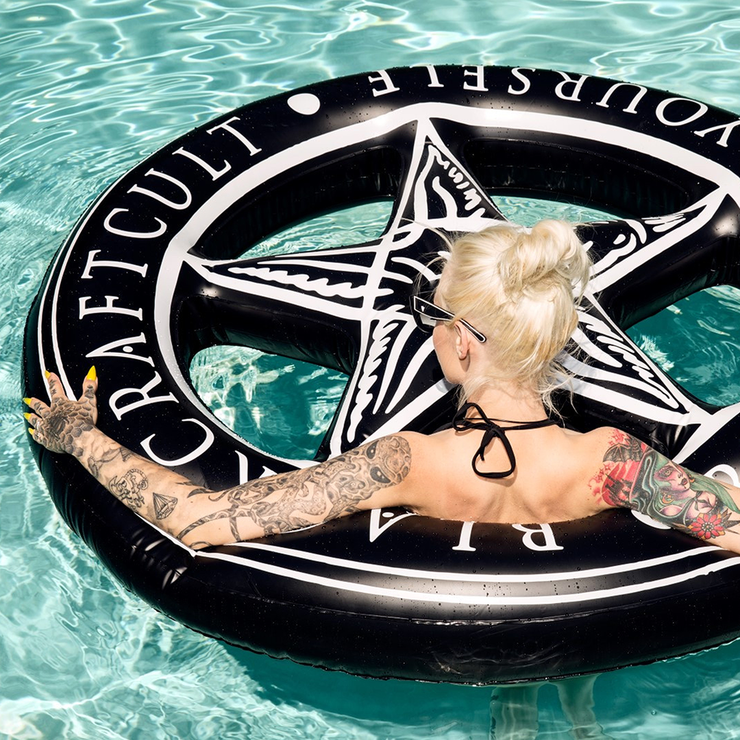 A black inflatable circular pool float with pentagram interior and custom blackcraft artwork. 