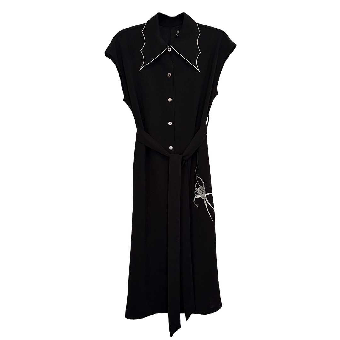 A classic black shirt dress with a spider web inspired collar with contrast white trim, an embroidered spider detail, a button front, short sleeves, and an adjustable waist tie. 