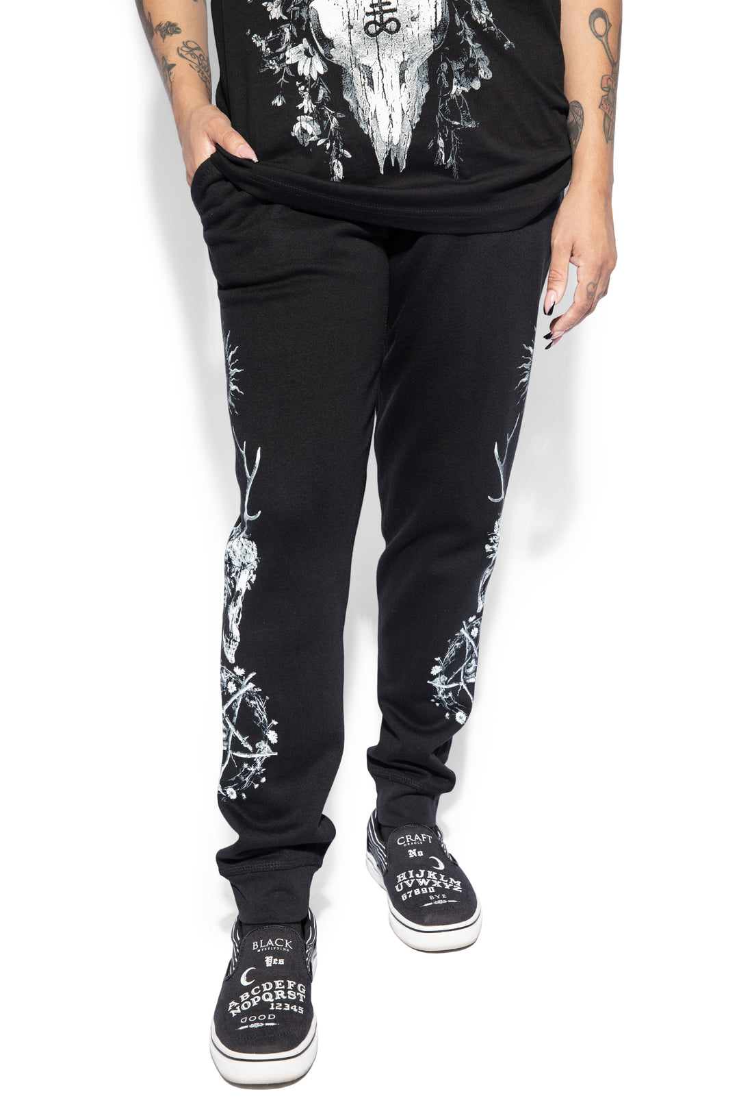 A model wearing a pair of classic fit black joggers with custom Blackcraft artwork along the sides of each leg.