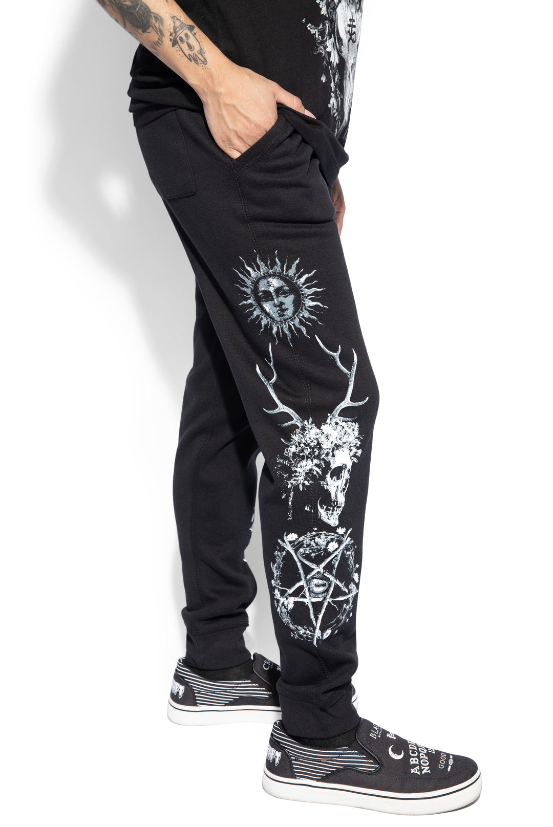 A model wearing a pair of classic fit black joggers with custom Blackcraft artwork along the sides of each leg.