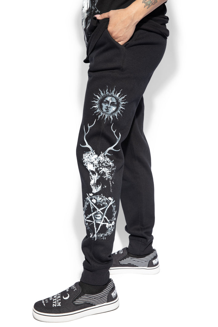 A model wearing a pair of classic fit black joggers with custom Blackcraft artwork along the sides of each leg.