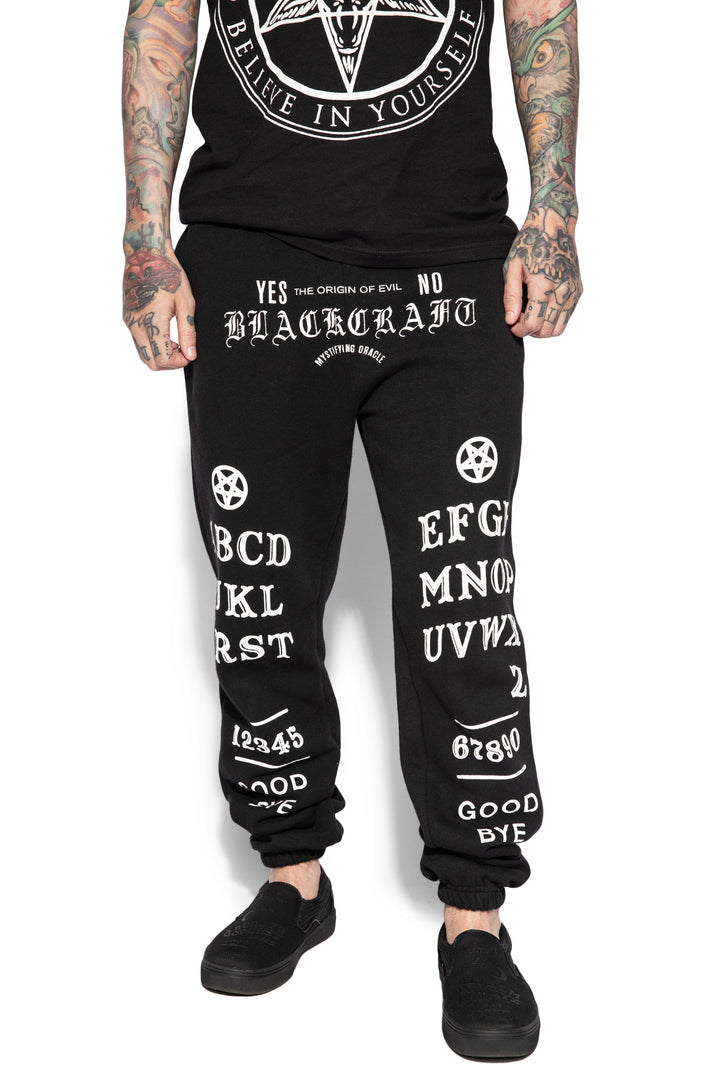 A model wearing a pair of classic fit black sweatpants with custom Blackcraft artwork along the front of each leg.