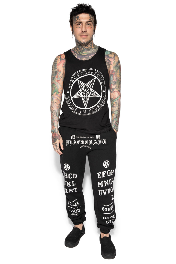 A model wearing a pair of classic fit black sweatpants with custom Blackcraft artwork along the front of each leg.