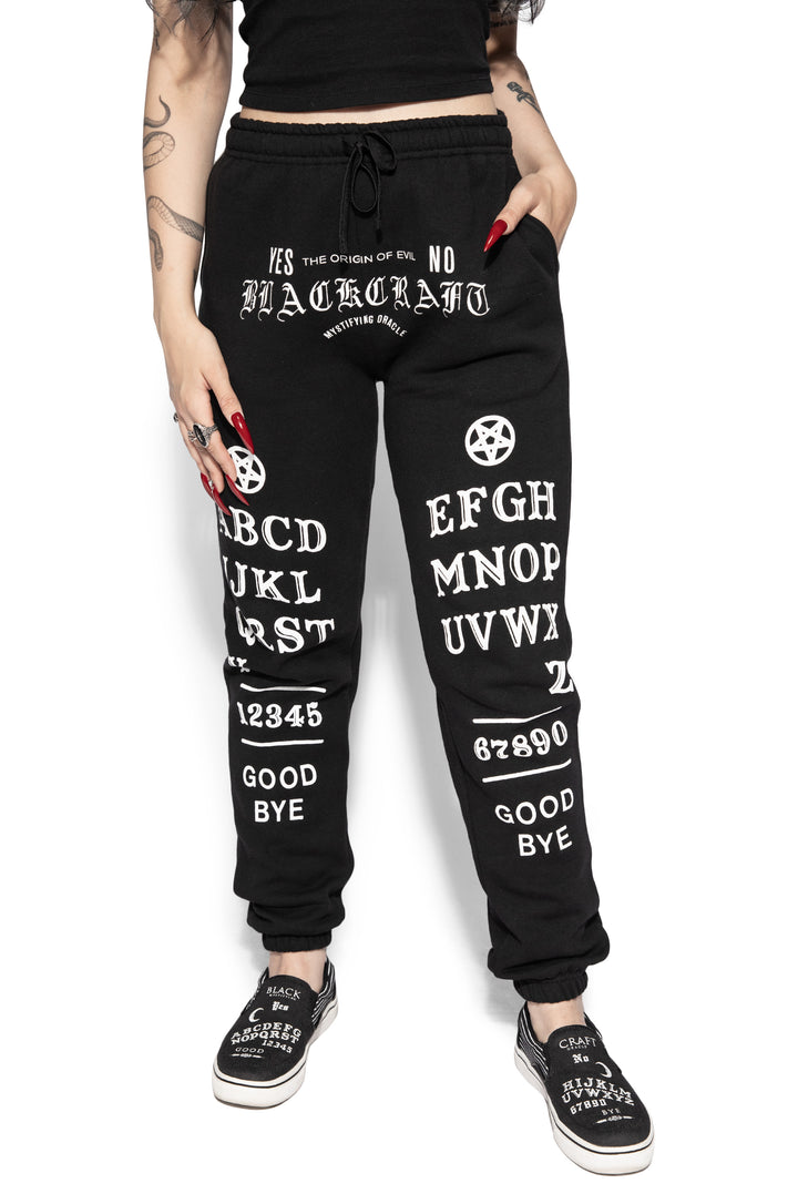 A model wearing a pair of classic fit black sweatpants with custom Blackcraft artwork along the front of each leg.