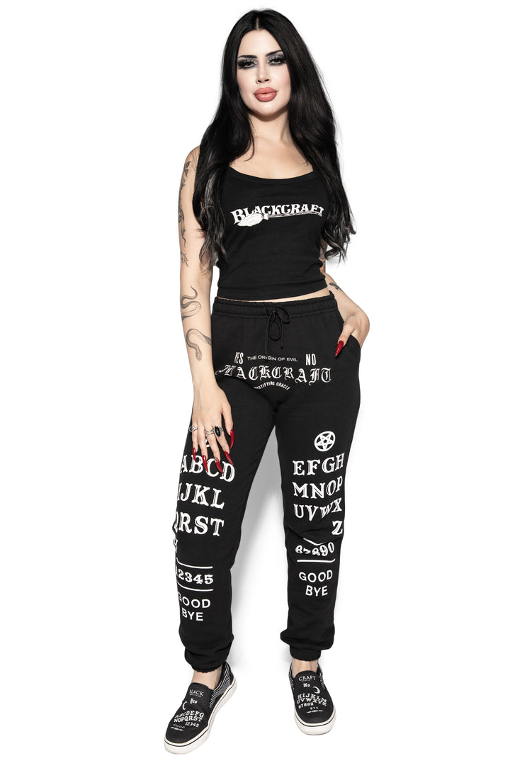 A model wearing a pair of classic fit black sweatpants with custom Blackcraft artwork along the front of each leg.