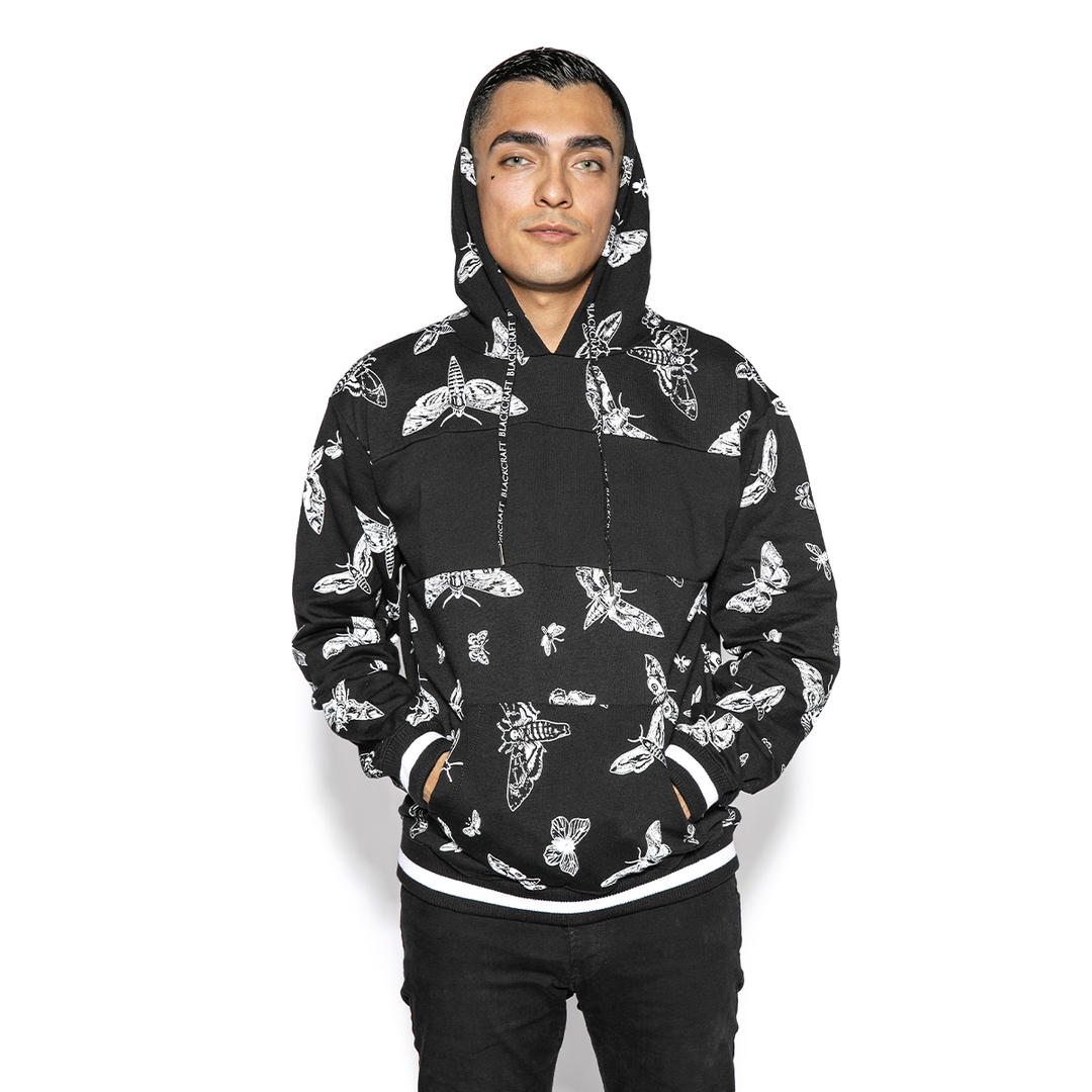 A model wearing a black and white pullover hoodie with custom Blackcraft moth artwork