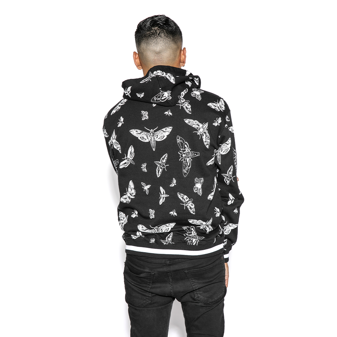 A model wearing a black and white pullover hoodie with custom Blackcraft moth artwork