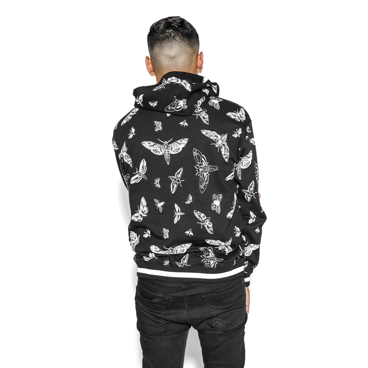 A model wearing a black and white pullover hoodie with custom Blackcraft moth artwork