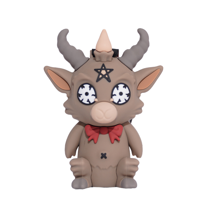 A cartoon-style goat figurine with gray horns, a beige-brown body, a red bow tie, and a black pentagram symbol on its forehead.