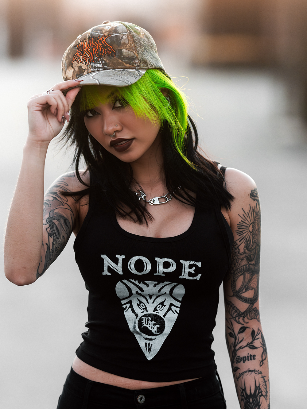 A model standing outside wearing a real camo print hat with orange Blackcraft logo on the front. 
