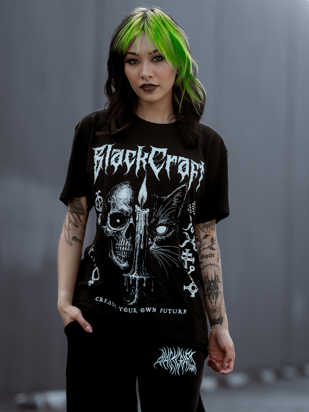 A green haired model standing outside wearing a classic black cotton tee with custom Blackcraft artwork across the front. 