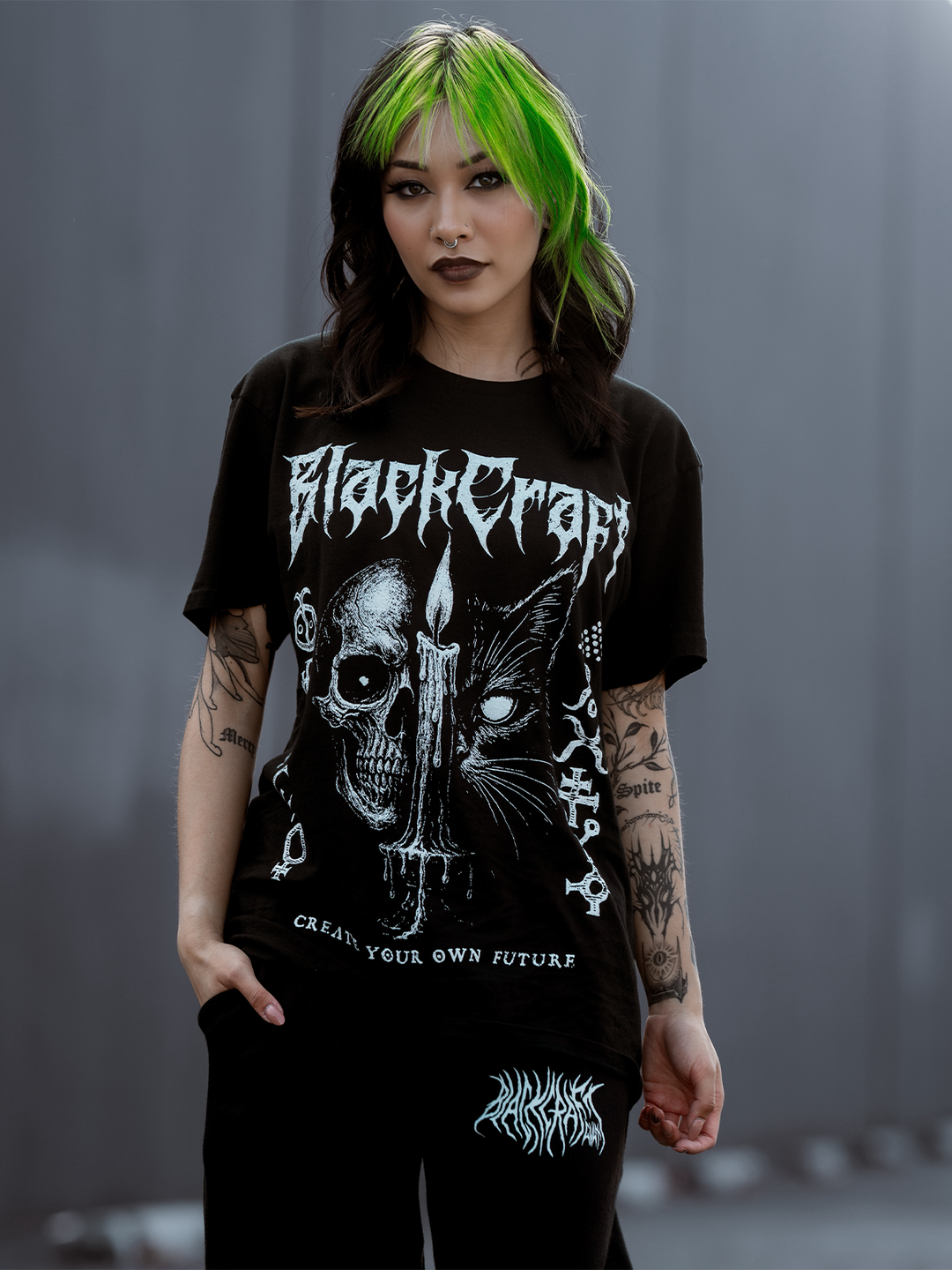 A green haired model standing outside wearing a classic black cotton tee with custom Blackcraft artwork across the front. 