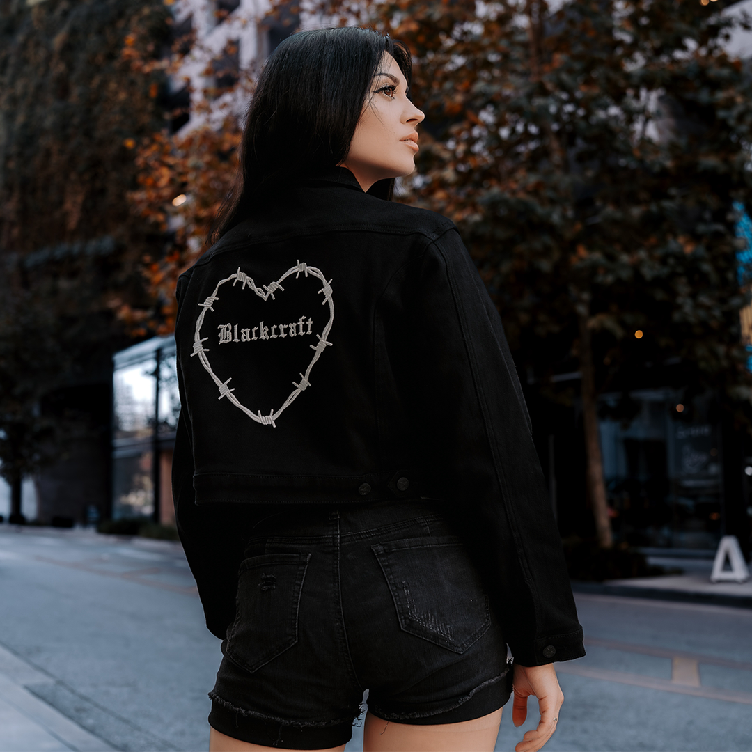 A classic black denim jacket with embroidered barbed wire heart design at the back.
