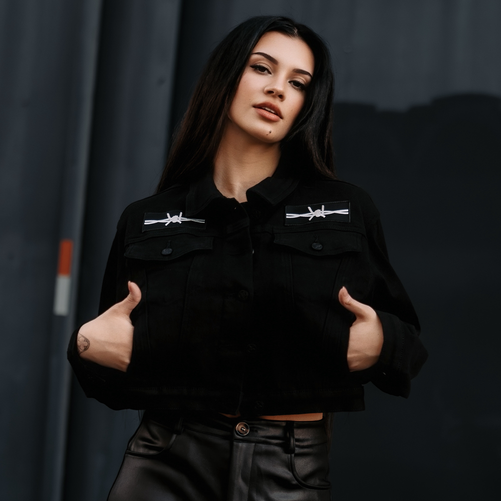 A classic black denim jacket with embroidered barbed wire heart design at the back.