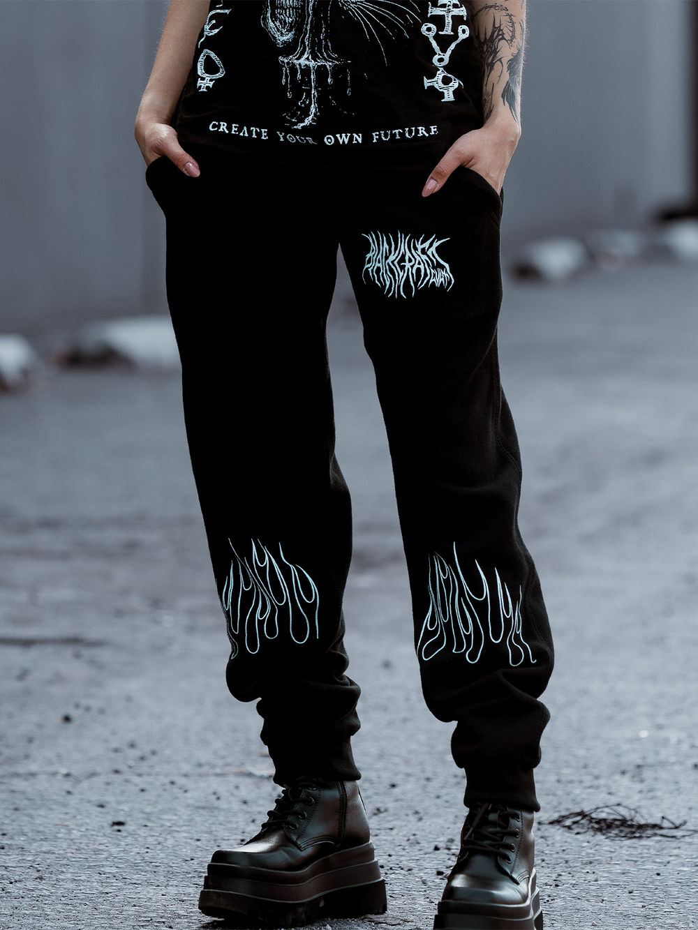 A model standing outside wearing classic black fleece unisex joggers with custom artwork from Blackcraft.