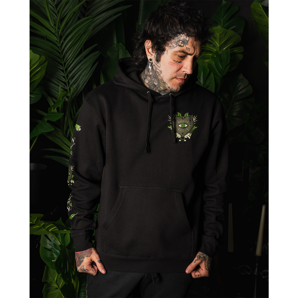 A model wearing a classic fit black Blackcraft pullover hoodie with custom plant witch artwork on the front, back, and along the sleeves.