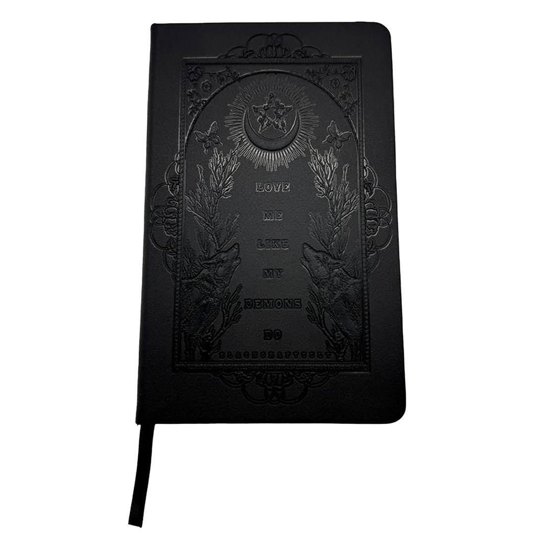 A black debossed journal with Love Me Like My Demons Do artwork on the front cover, from Blackcraft.