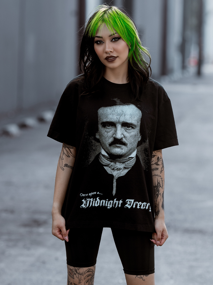 A green haired model standing outside wearing a classic black cotton boxy tee with Edgar Allen poe and the Raven artwork, from Blackcraft.