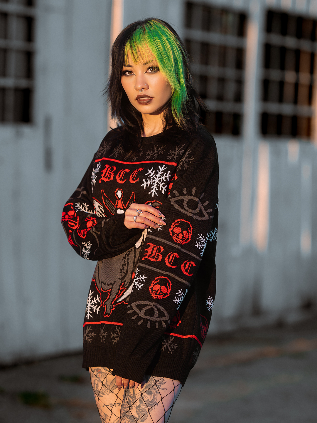 A model standing outside wearing a gothic black, red, and white spooky Mothman holiday sweater, from Blackcraft. 