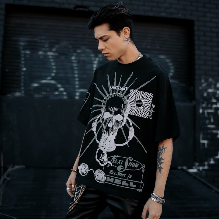A model standing outside wearing a heavyweight oversized black tee with custom artwork on the front and right sleeve, from Blackcraft.
