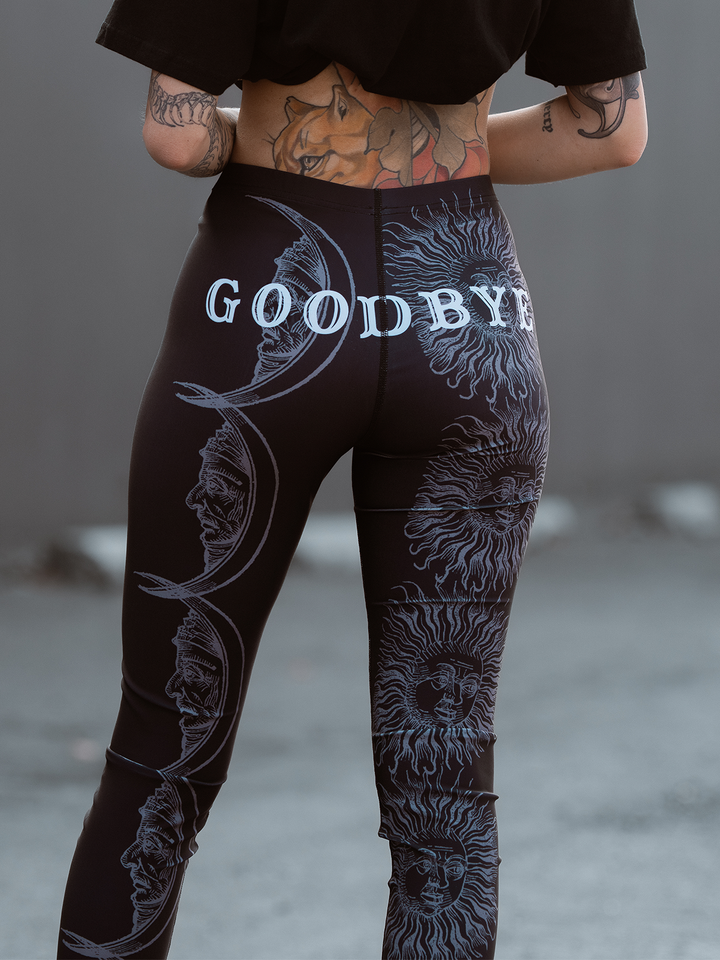 A model standing outside wearing classic women's black leggings with an allover ouija print. 