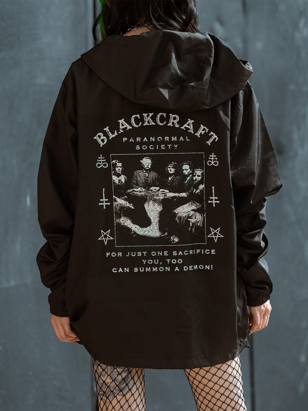 A model standing outside wearing a classic black water resistant windbreaker jacket with custom Ouija artwork from Blackcraft.