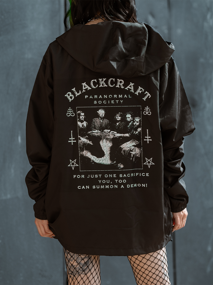 A model standing outside wearing a classic black water resistant windbreaker jacket with custom Ouija artwork from Blackcraft.