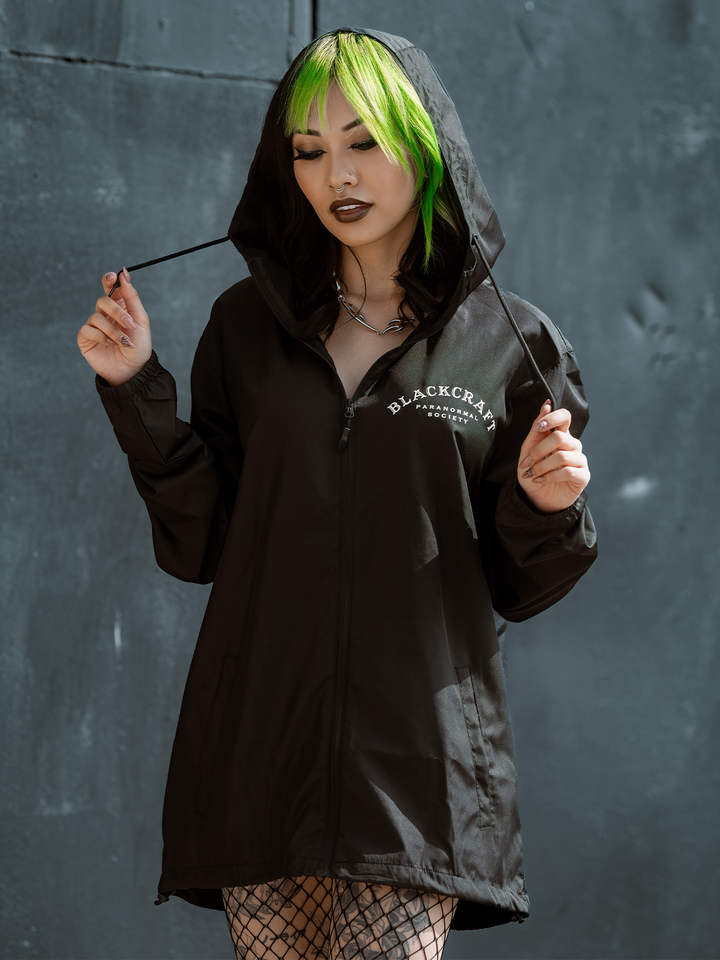 A model standing outside wearing a classic black water resistant windbreaker jacket with custom Ouija artwork from Blackcraft.