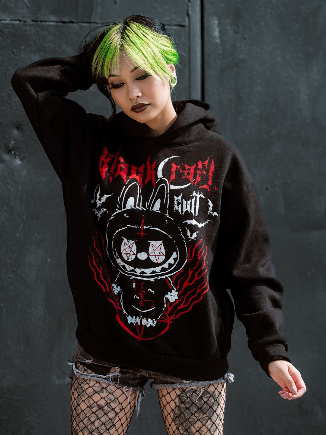 A green haired model wearing a classic black pullover hoodie with custom Blackcraft artwork on the front and side pockets.