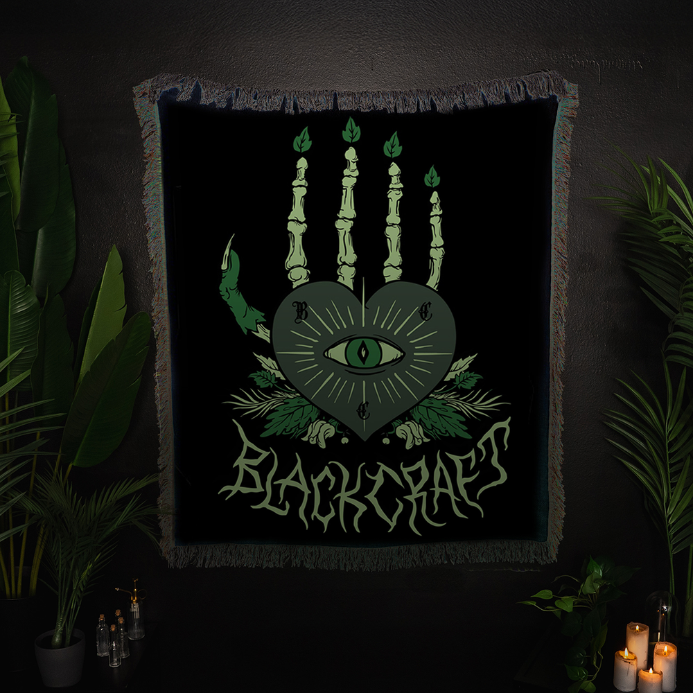 A large lightweight knit throw blanket with fringed trim and custom plant witch artwork, from Blackcraft.