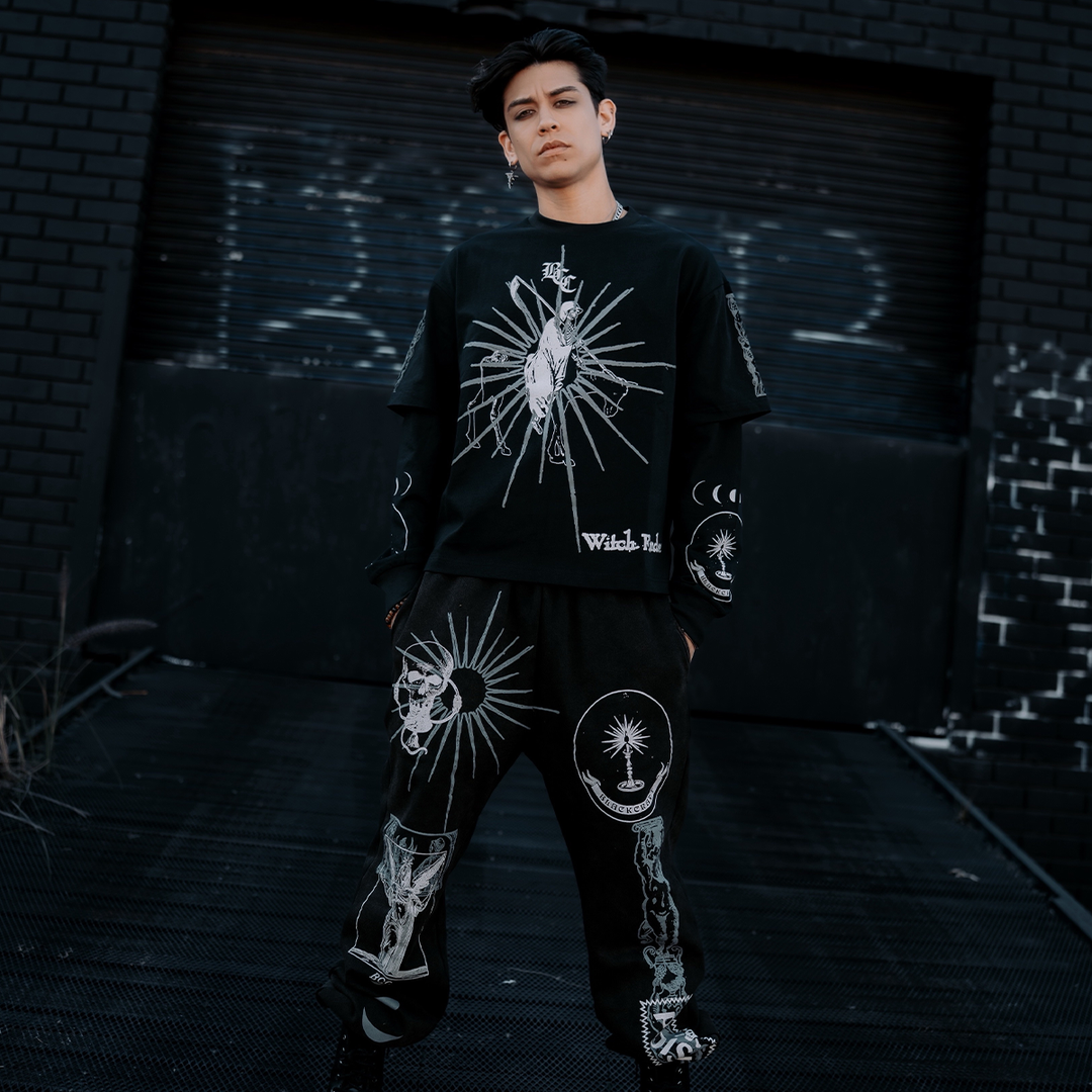 A model standing outside wearing classic sweatpants in a washed black with custom Blackcraft artwork on the front of both legs. 