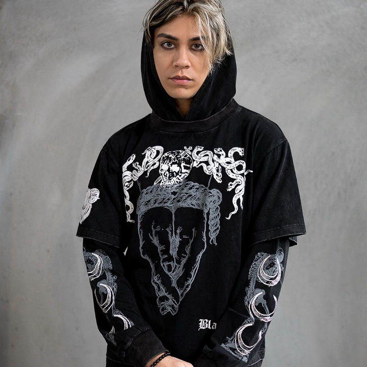 A model wearing a washed black long sleeve twofer pullover hoodie with custom Blackcraft artwork on the front and along the sleeves.