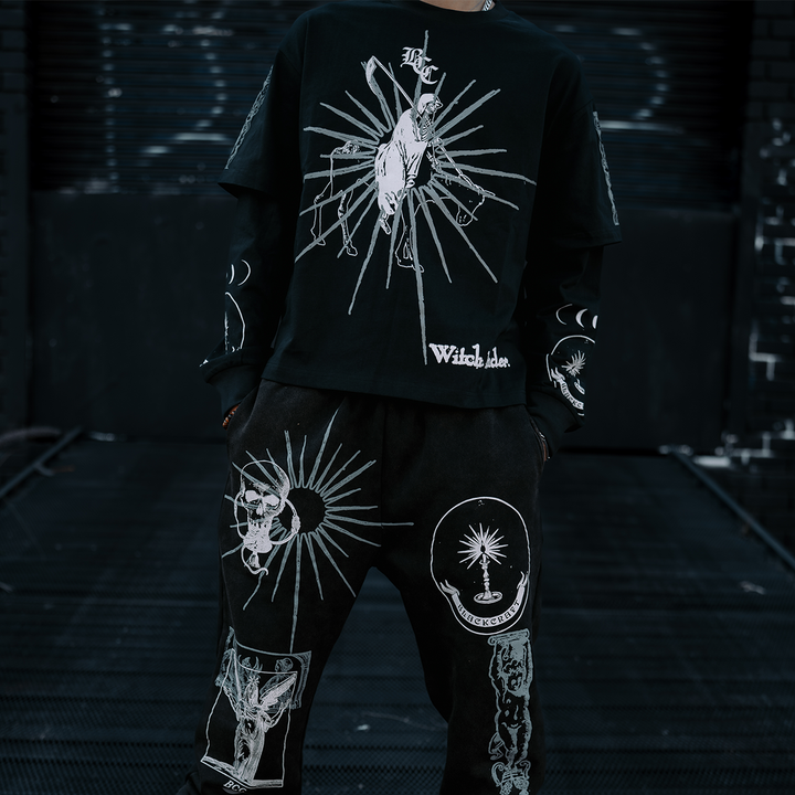 A model standing outside wearing classic sweatpants in a washed black with custom Blackcraft artwork on the front of both legs. 