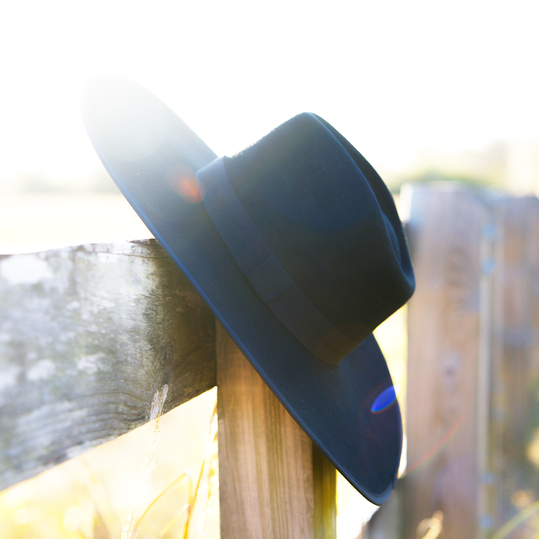 A gothic black wool felted hat with white cobweb detail at the inner brim.