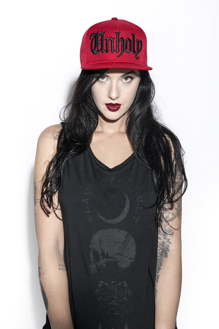 A classic red baseball cap with embroidered unholy across the front.