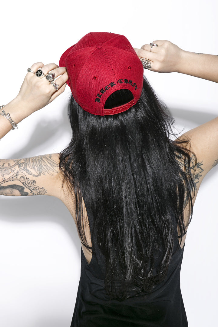A classic red baseball cap with embroidered unholy across the front.