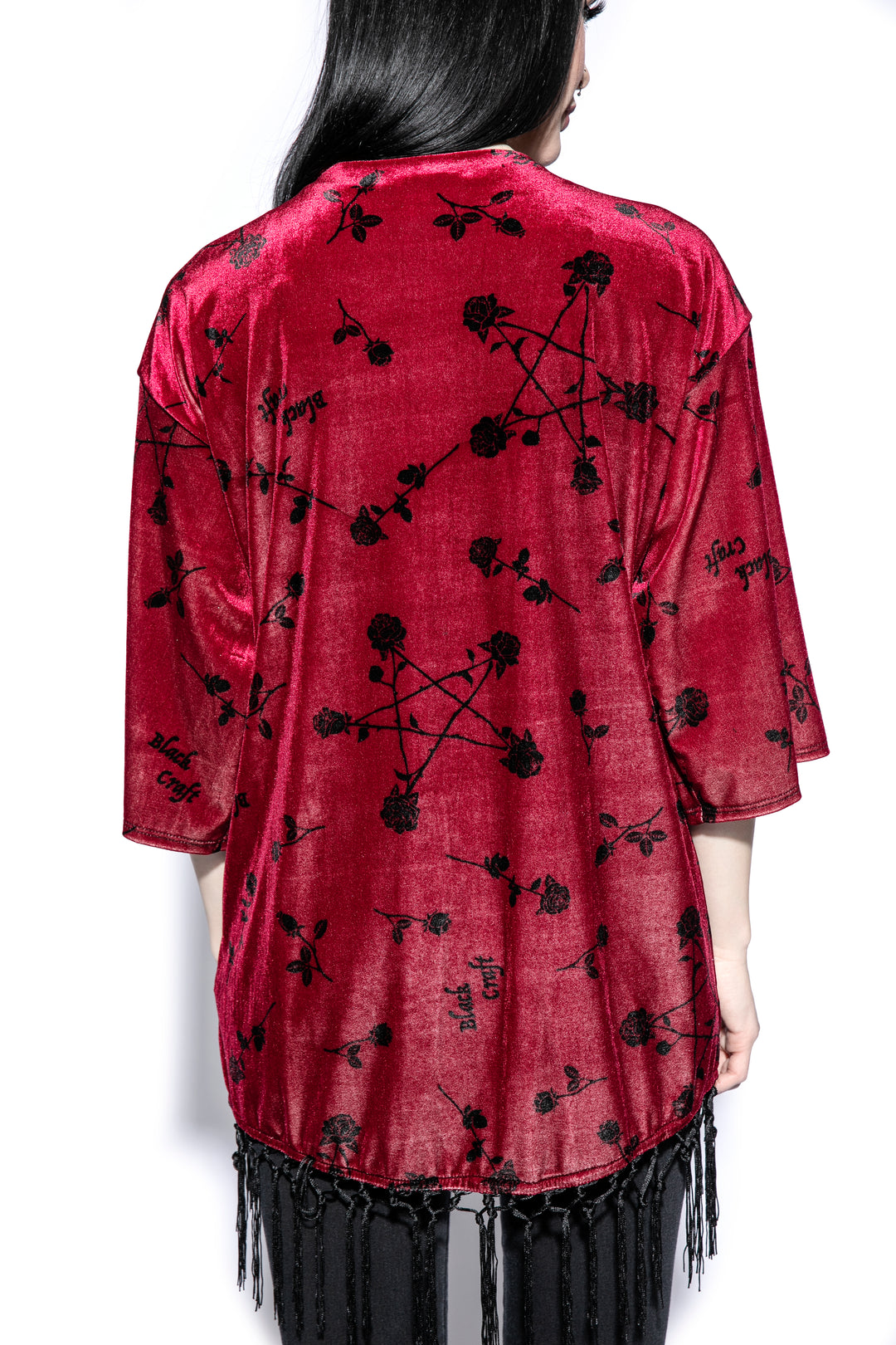 A gothic velvet kimono cover up with fringed trim, an open front, and kimono half length sleeves.