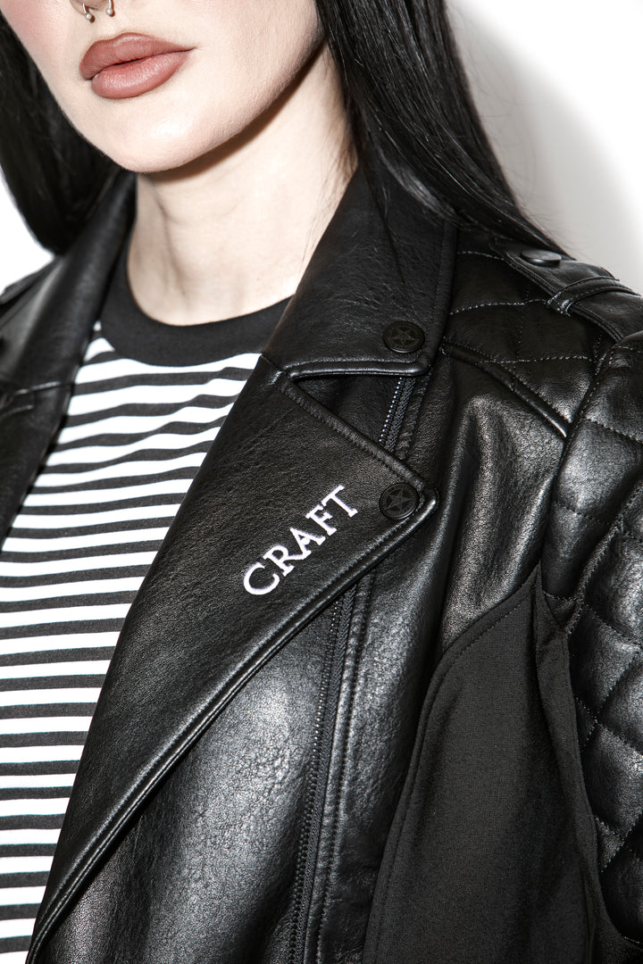 A black haired model wearing a classic black faux leather jacket from Blackcraft.