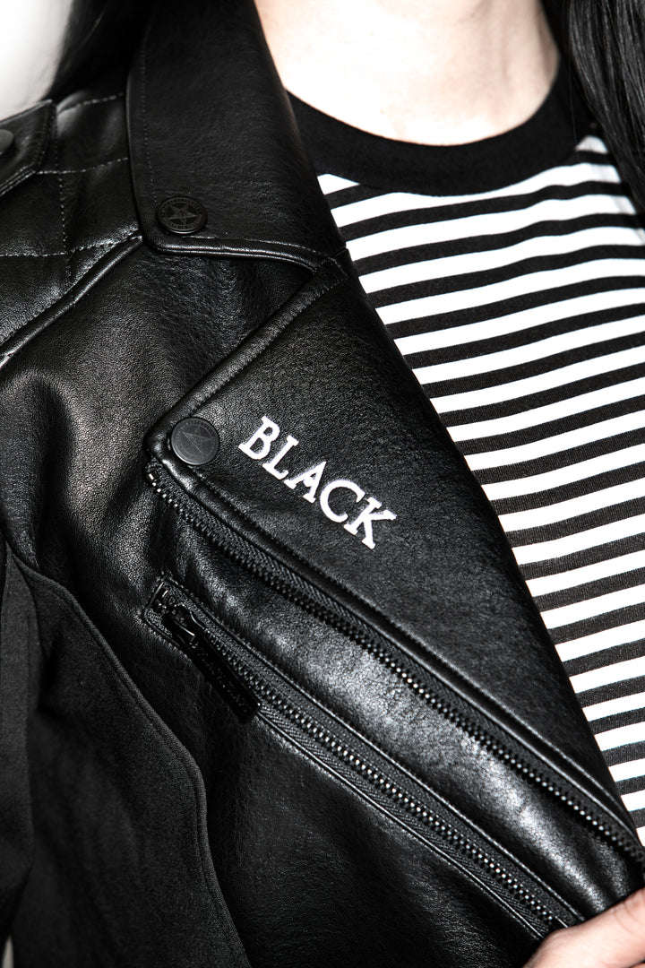 A black haired model wearing a classic black faux leather jacket from Blackcraft.