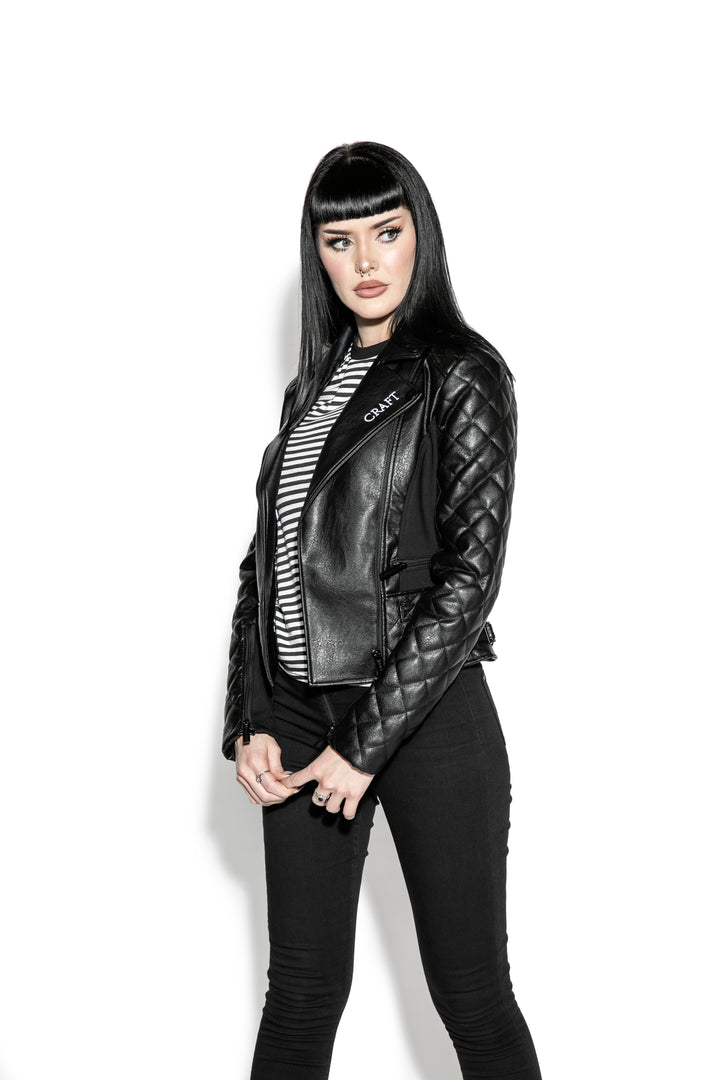 A black haired model wearing a classic black faux leather jacket from Blackcraft.